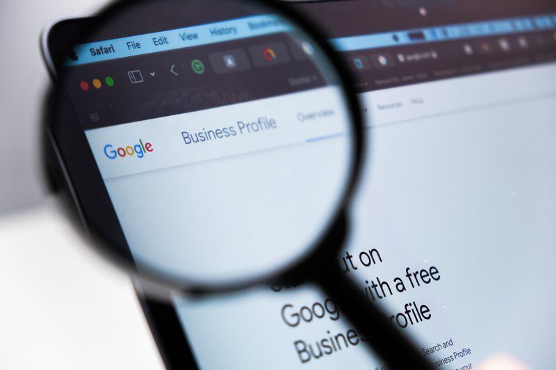 Google Business Profile logo enlarged through a magnifying glass on a laptop screen, December 2023, Prague, Czech Republic