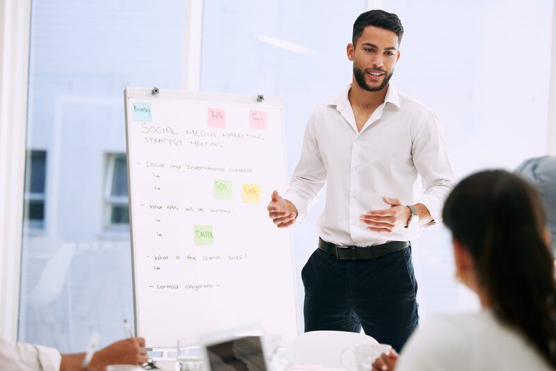 Whiteboard, presentation and business people with manager in meeting for social media marketing, ideas and planning. Presenter or man speaking to employees, creative agency and training for project.